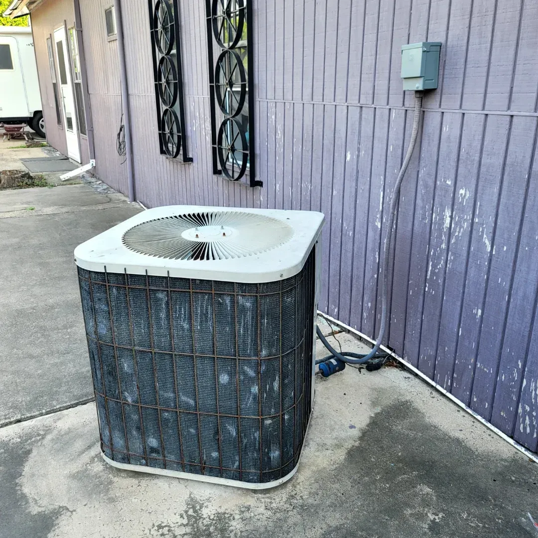 Two air conditioners are sitting outside of a house.