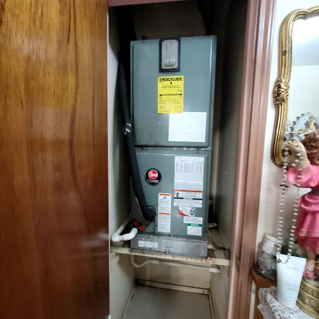 An air conditioner is sitting in a closet next to a mirror.