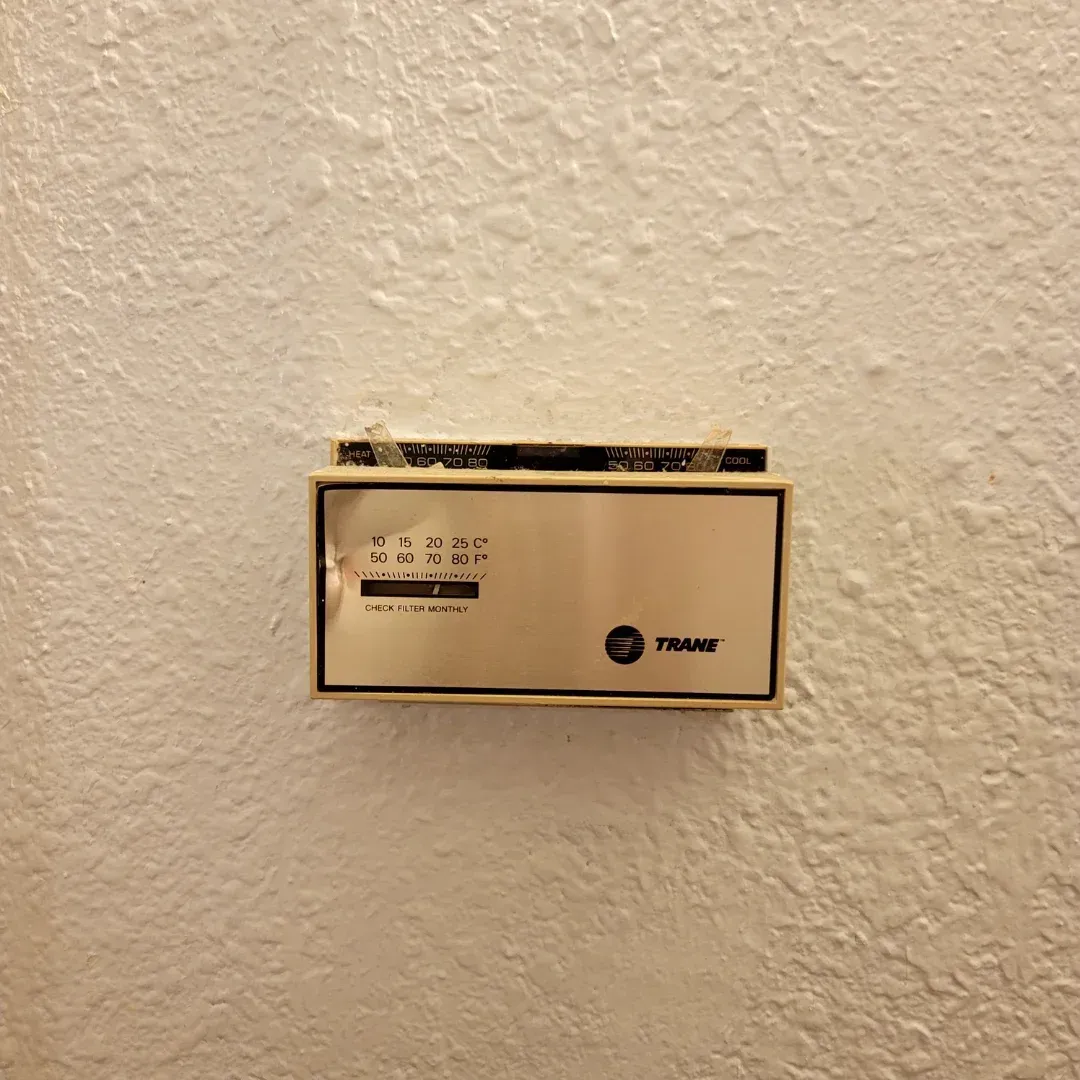 A thermostat is hanging on a white wall.
