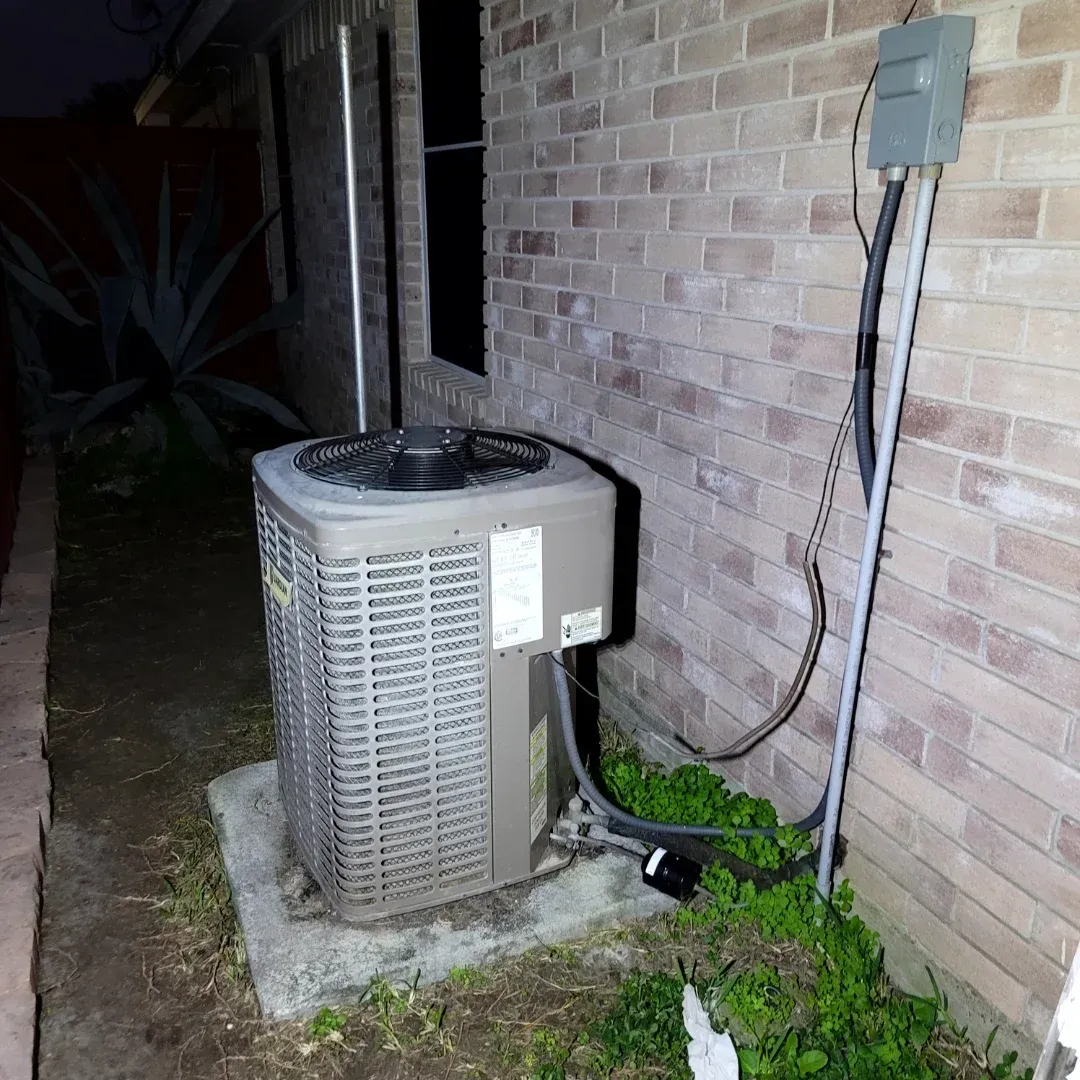 An air conditioner is sitting outside of a brick building