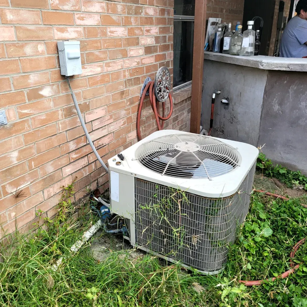 An air conditioner is sitting on the side of a brick building.