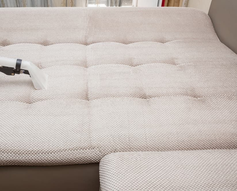 Person Using a Cleaning Tool on A Beige Tufted Sofa — Totally Green Cleaning Solutions in Belconnen, ACT