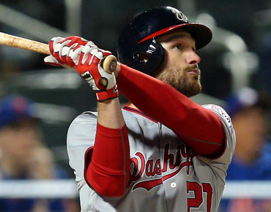 Baseball player in a gray and red uniform batting, Washington Nationals logo visible.