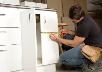Carpenter taking cupboard measurements