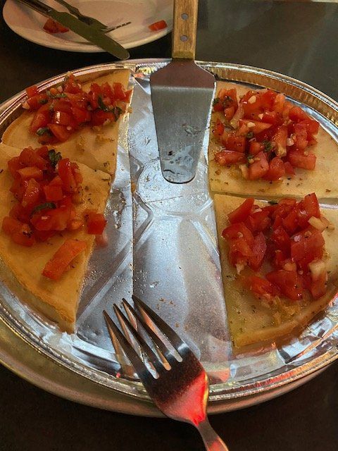 A plate of food with tomatoes and a spatula and a fork
