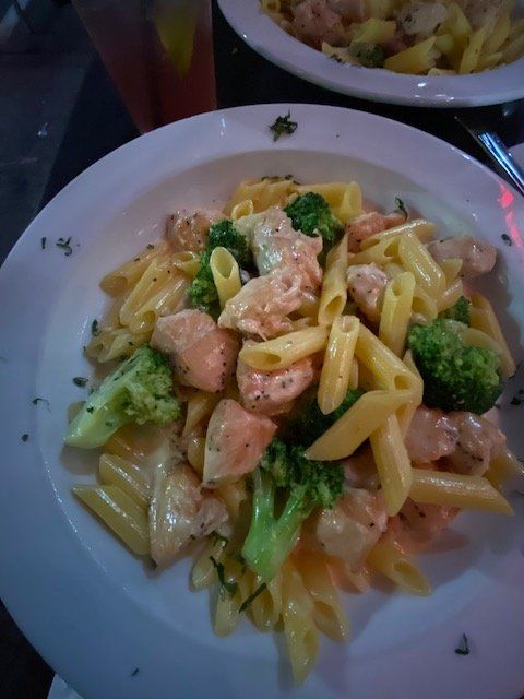 A plate of pasta with broccoli and chicken on a table