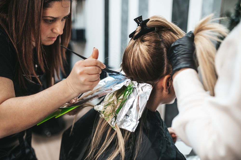 Hair Stylist Applying Foils to a Client’s Hair During a Salon Coloring Service — Fraser Shores Hair Design In Urraween, QLD