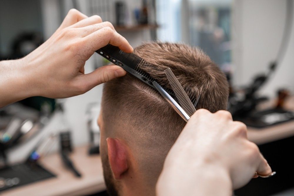 A Man is Getting His Hair Cut by a a Comb and Scissors — Fraser Shores Hair Design In Urraween, QLD