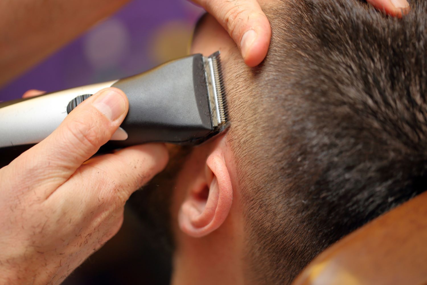 A Man is Getting His Hair Cut by a Barber With a Clipper — Fraser Shores Hair Design in Fraser Coast, QLD