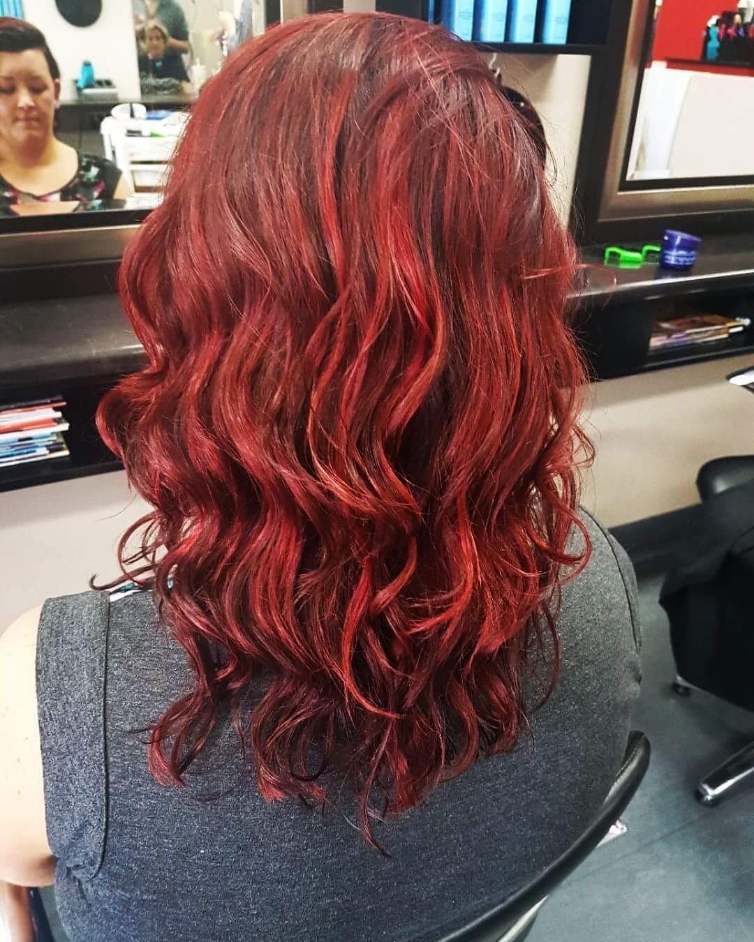 A Woman With Red Hair is Sitting in a Chair in Front of a Mirror — Fraser Shores Hair Design in Urraween, QLD