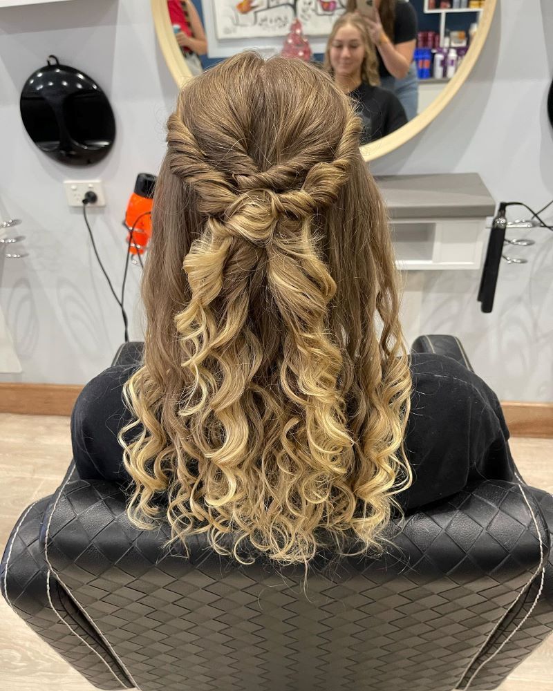 A Woman is Sitting in a Chair With Her Hair in a Half Up Half Down Hairstyle — Fraser Shores Hair Design in Fraser Coast, QLD