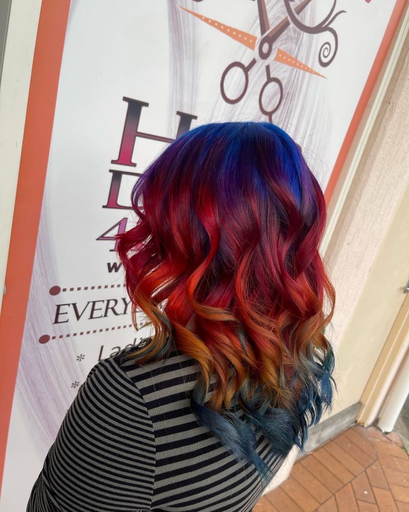 A Woman with Red and Blue Hair Is Standing in Front of A Sign — Fraser Shores Hair Design in Urraween, QLD