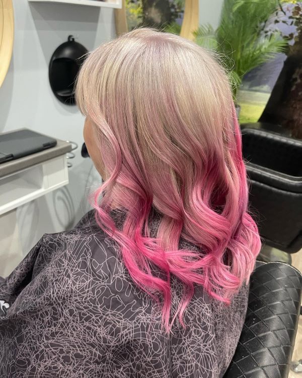 A Woman With Pink Hair is Sitting in a Chair in a Salon — Fraser Shores Hair Design in Fraser Coast, QLD