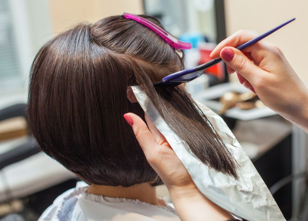 Hairdresser Applying Dye to Short Brown Hair With a Brush and Foils — Fraser Shores Hair Design In Urraween, QLD