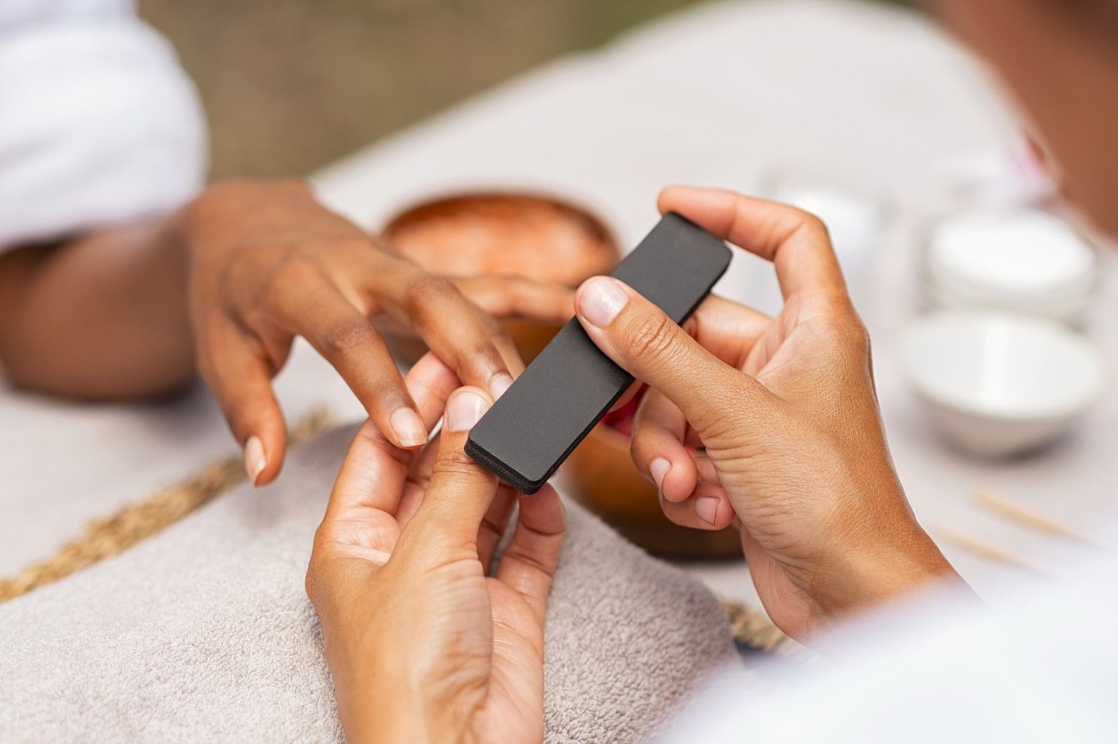 A Woman is Getting Her Nails Done at a Nail Salon Using a Stone — Fraser Shores Hair Design in Urraween, QLD