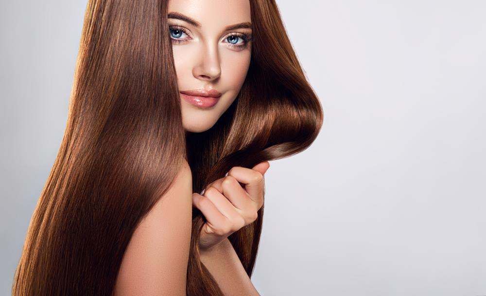 Woman with Long, Straight Brown Hair Smiling Against a Light Gray Background — Fraser Shores Hair Design In Urraween, QLD