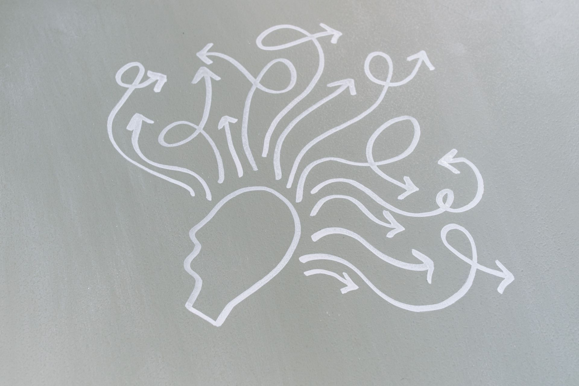 White line drawing of a human head with swirling arrows and circles above it, suggesting ideas or confusion