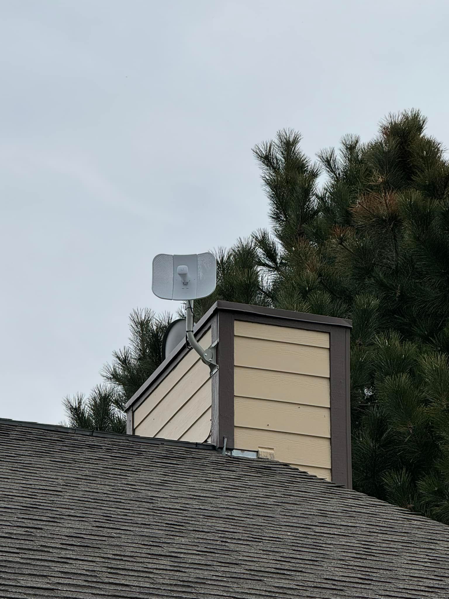 A roof with a chimney and a satellite dish on it.