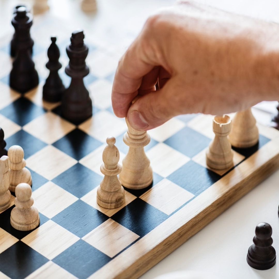 A person is playing a game of chess and moving a piece