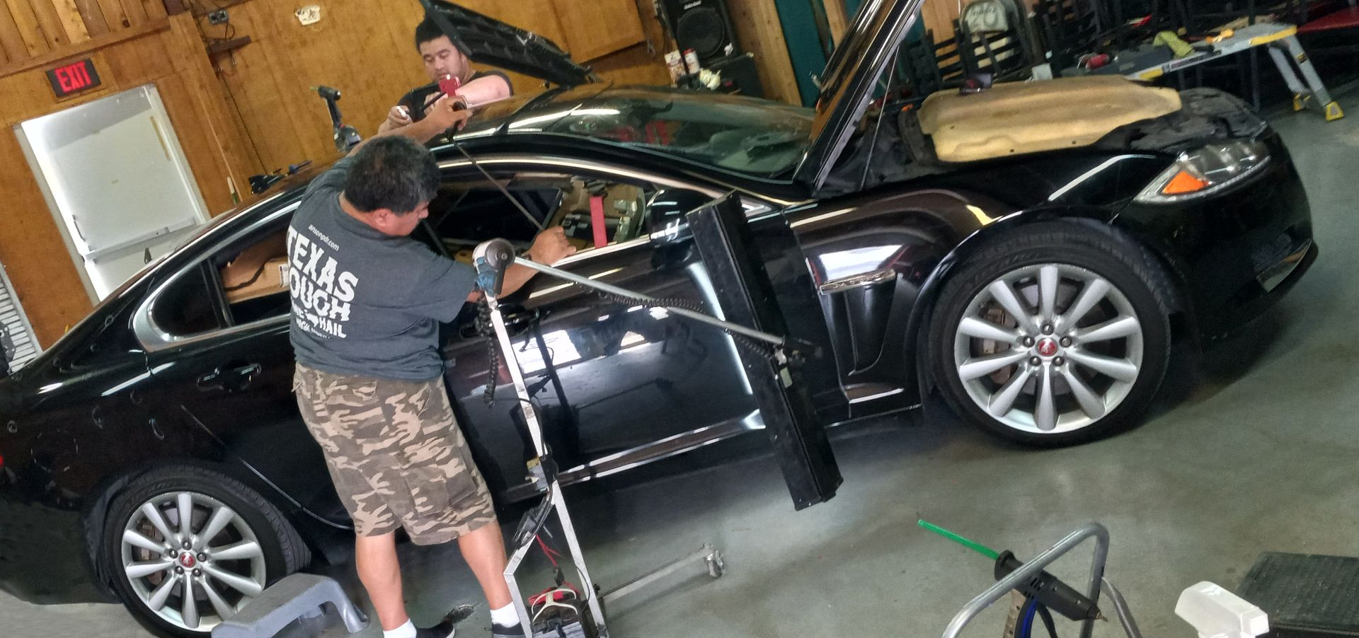 Silver car hood reflecting trees and sky on a sunny day.