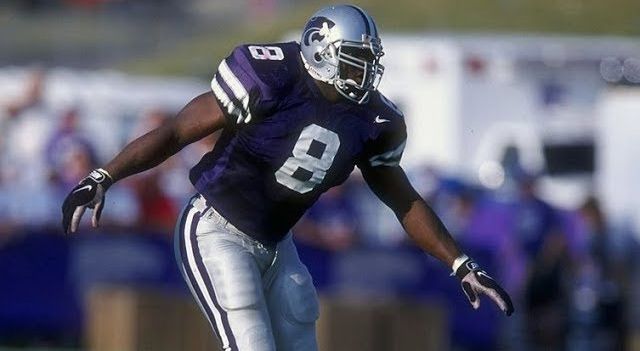 Football player in purple uniform, number 8, preparing to play on a sunny field.