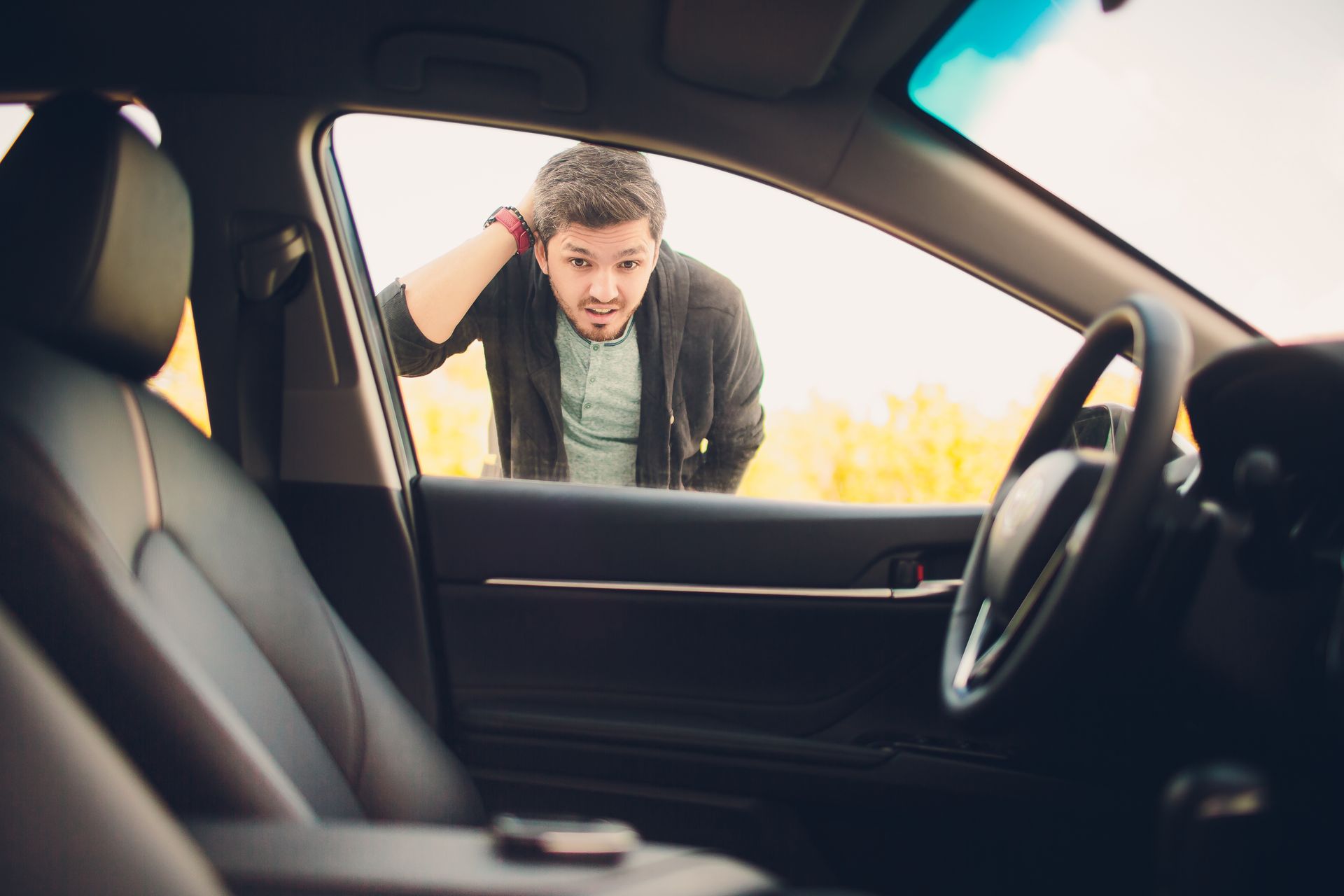 A man stands outside the car, looking in with a worried, locked-out expression.