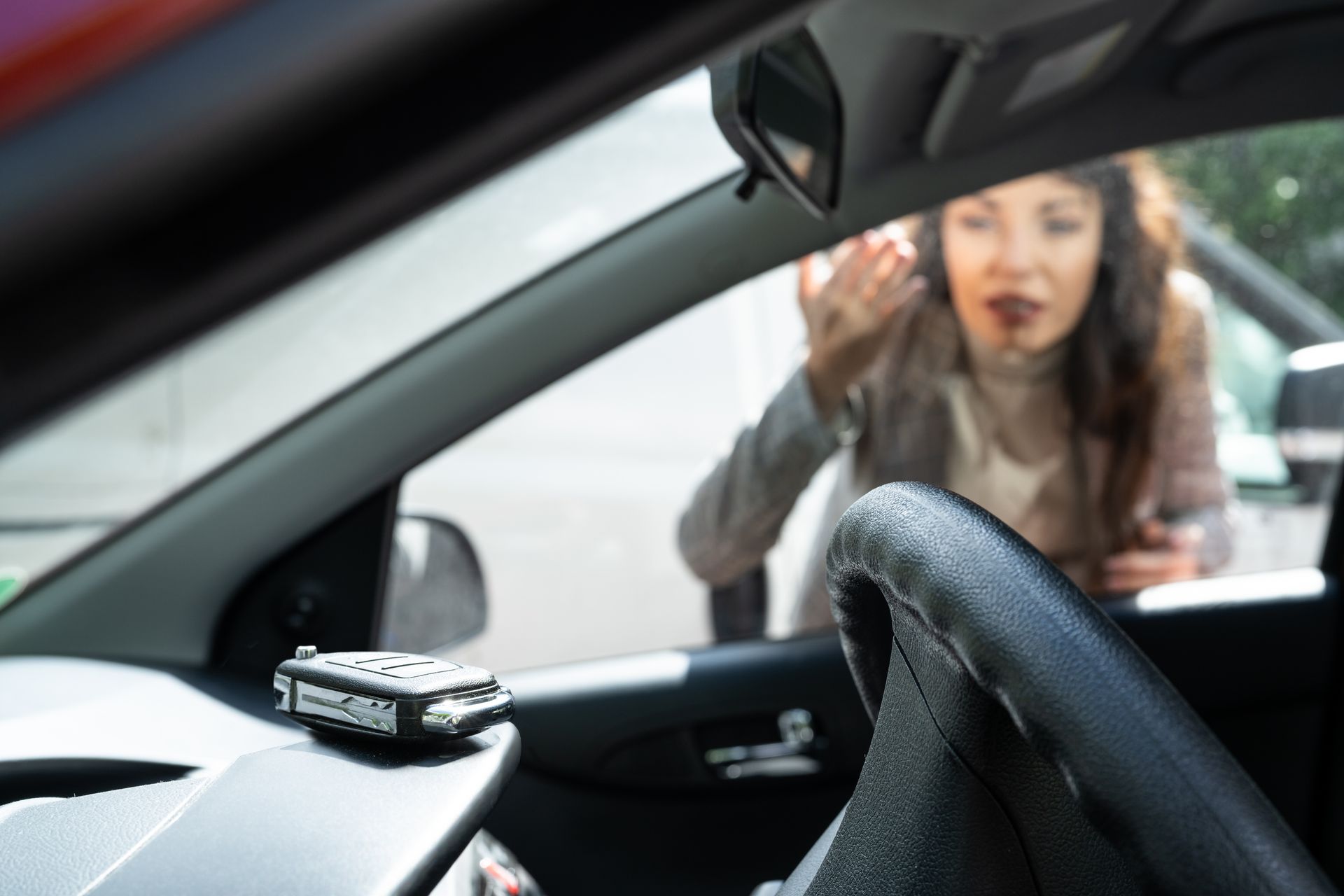 Frustrated woman looks at her locked keys in car through the window after a stressful lockout. Frustrated woman looks at her locked keys in car through the window after a stressful lockout.