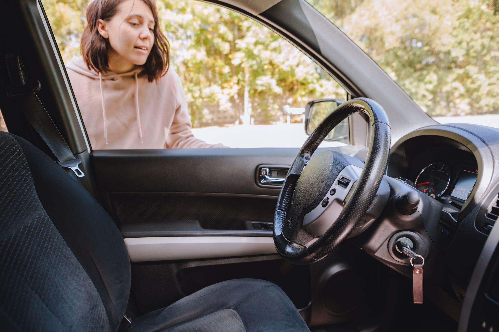 A woman standing outside her car looking at keys locked inside the vehicle. A woman standing outside her car looking at keys locked inside the vehicle.