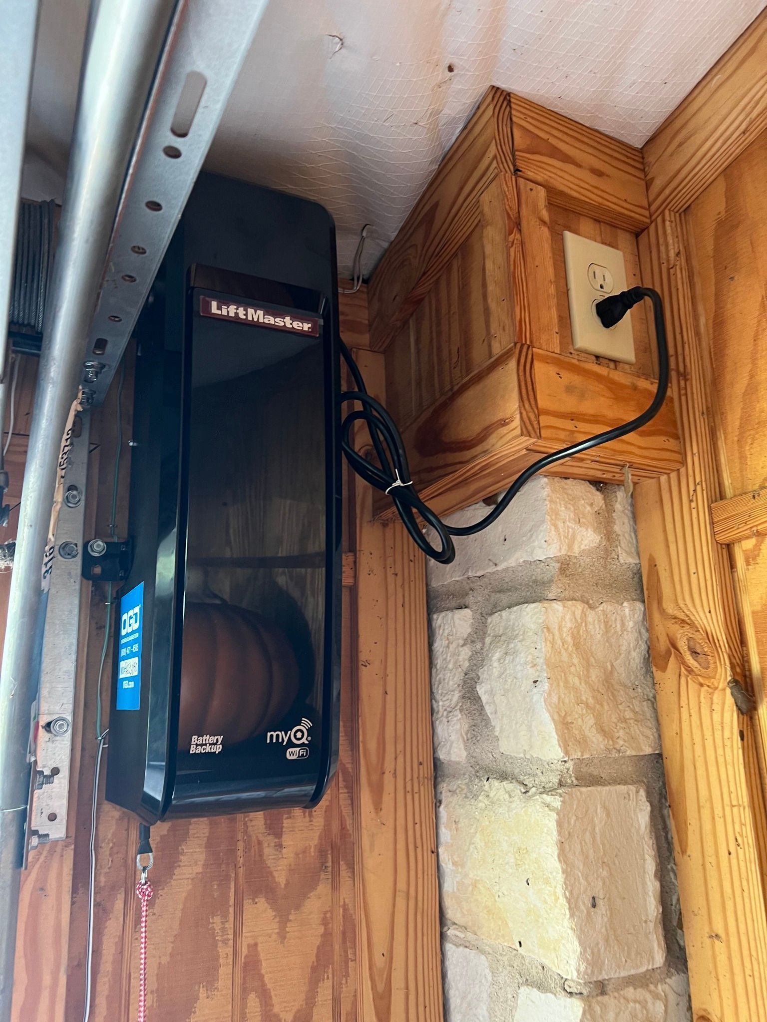 A garage door opener is hanging from the ceiling next to a wooden box.