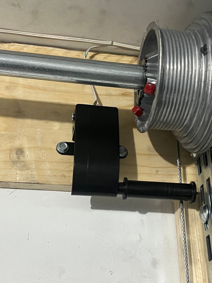 A close up of a garage door spring on a wooden shelf.