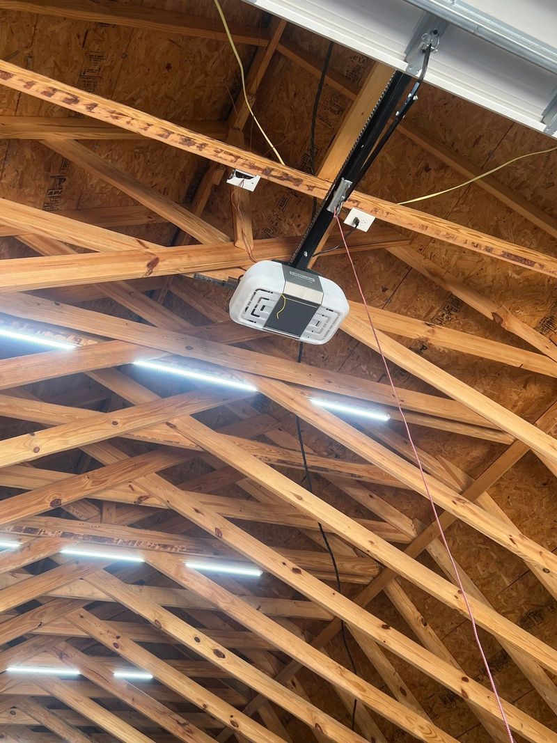 A garage door opener is hanging from the ceiling of a building.
