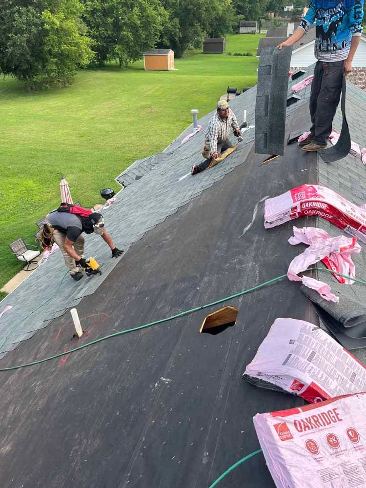 Roofers installing shingles on a house roof on a sunny day.