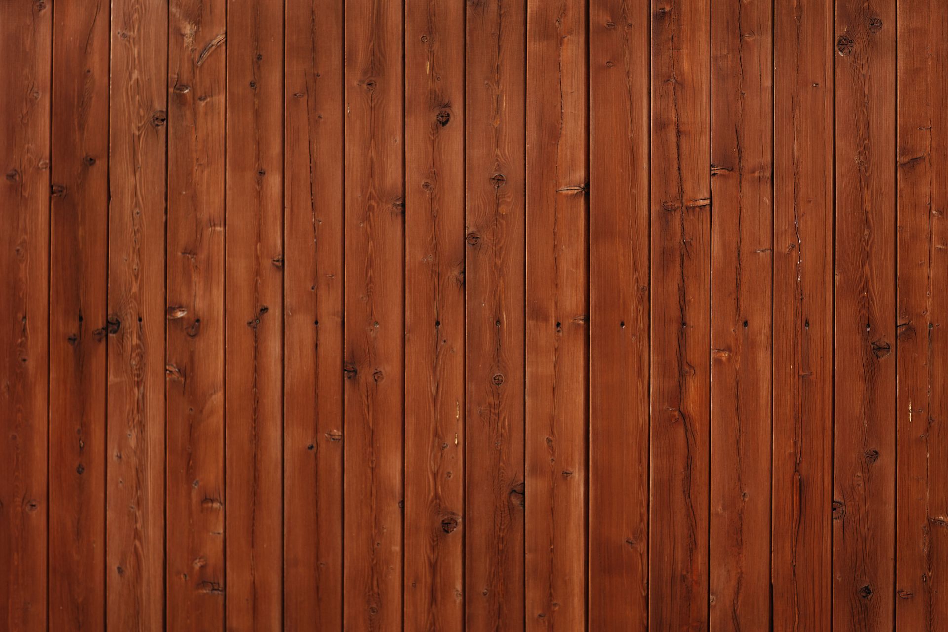 Close-up of brown wooden cladding, focusing on the vertical lines and the wood's natural grain.
