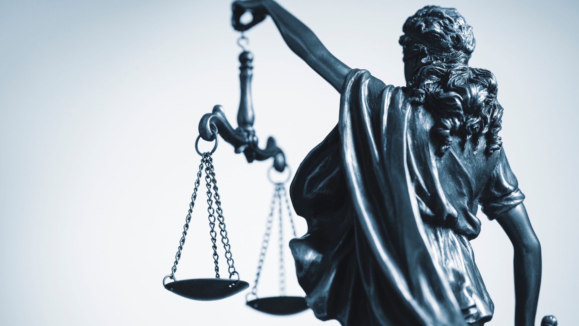 Statue of Lady Justice holding scales and sword against a light background