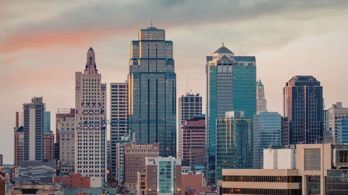 City skyline with modern high-rises at sunset under a pink and blue sky