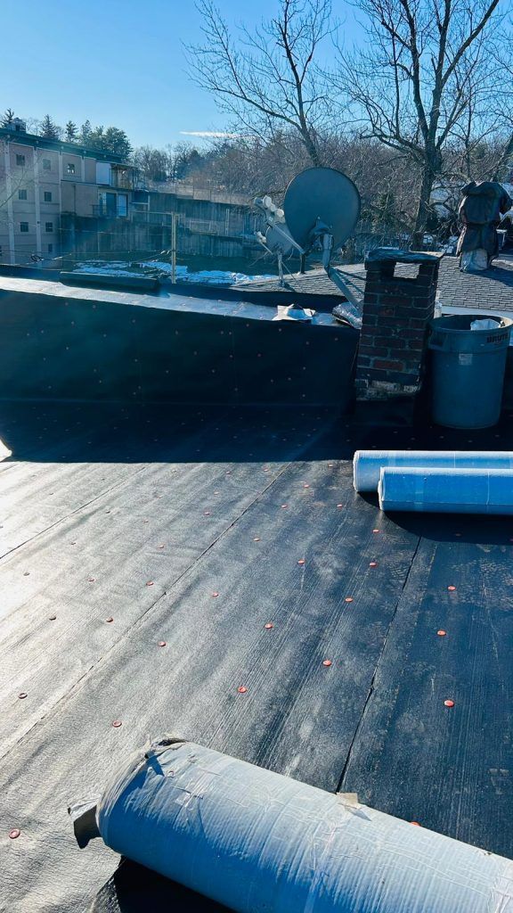 A roof with rolls of asphalt sitting on top of it.