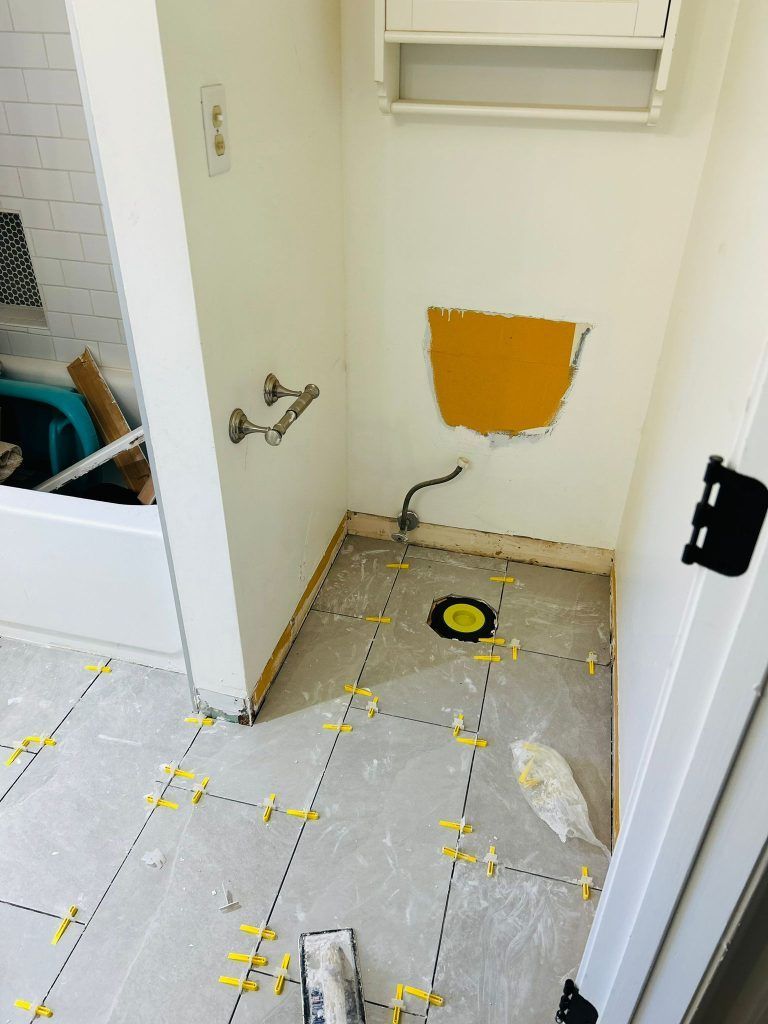 A bathroom with a hole in the wall and tiles on the floor.