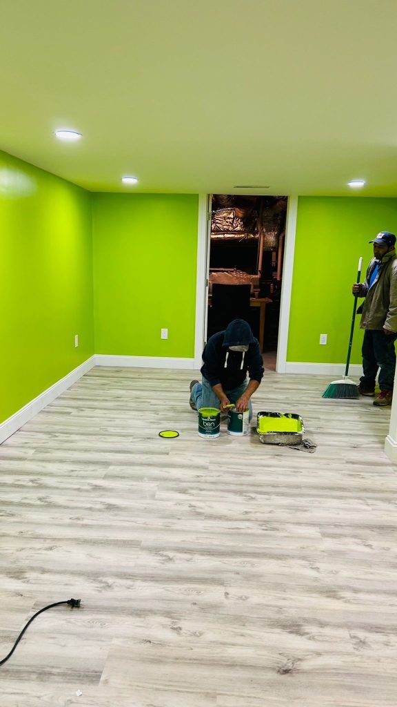 A man is kneeling on the floor in a room with green walls.