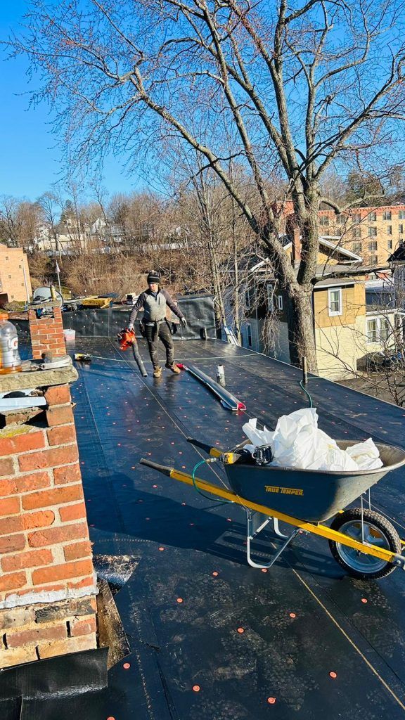 A wheelbarrow filled with snow is sitting on top of a roof.