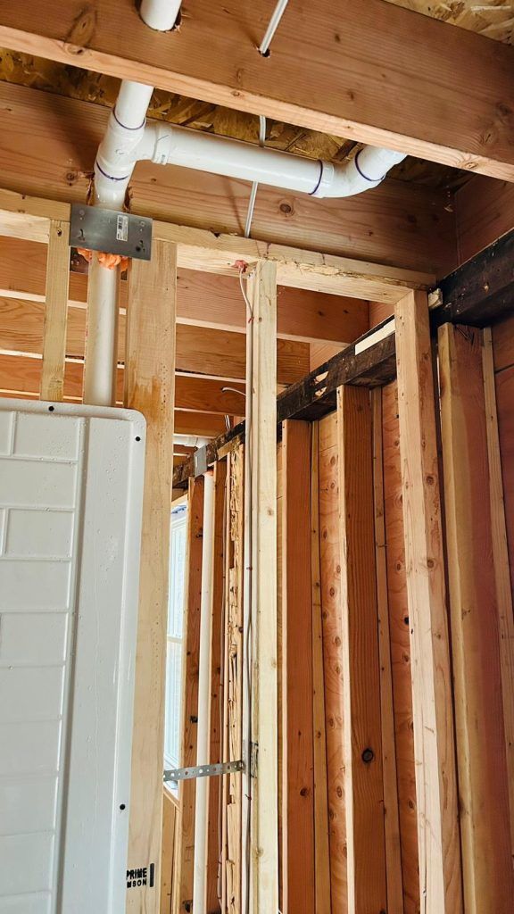 A house is being built with wooden beams and pipes coming out of the ceiling.