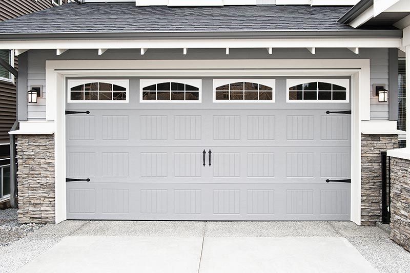 A gray garage door is sitting in front of a house.