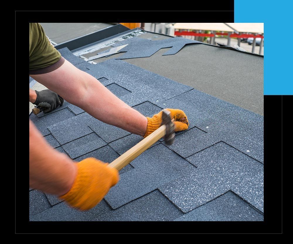A man is hammering a roof with a hammer.