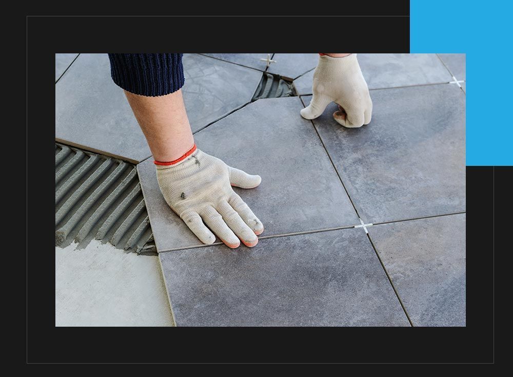 A person is laying tiles on a floor.