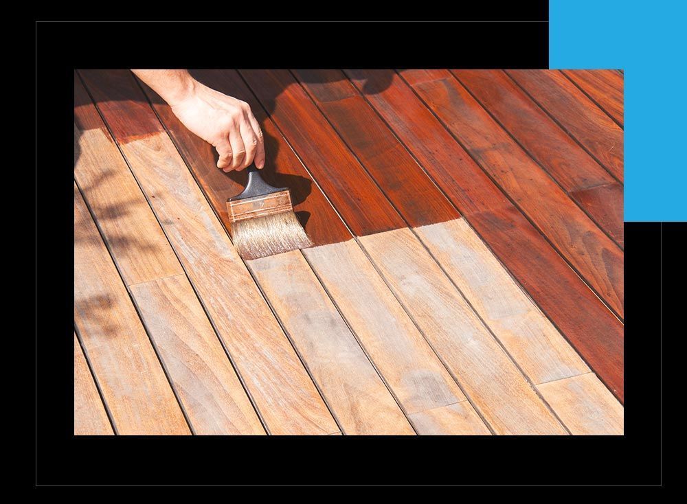 A person is painting a wooden deck with a brush.