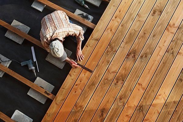 A man is working on a wooden deck.