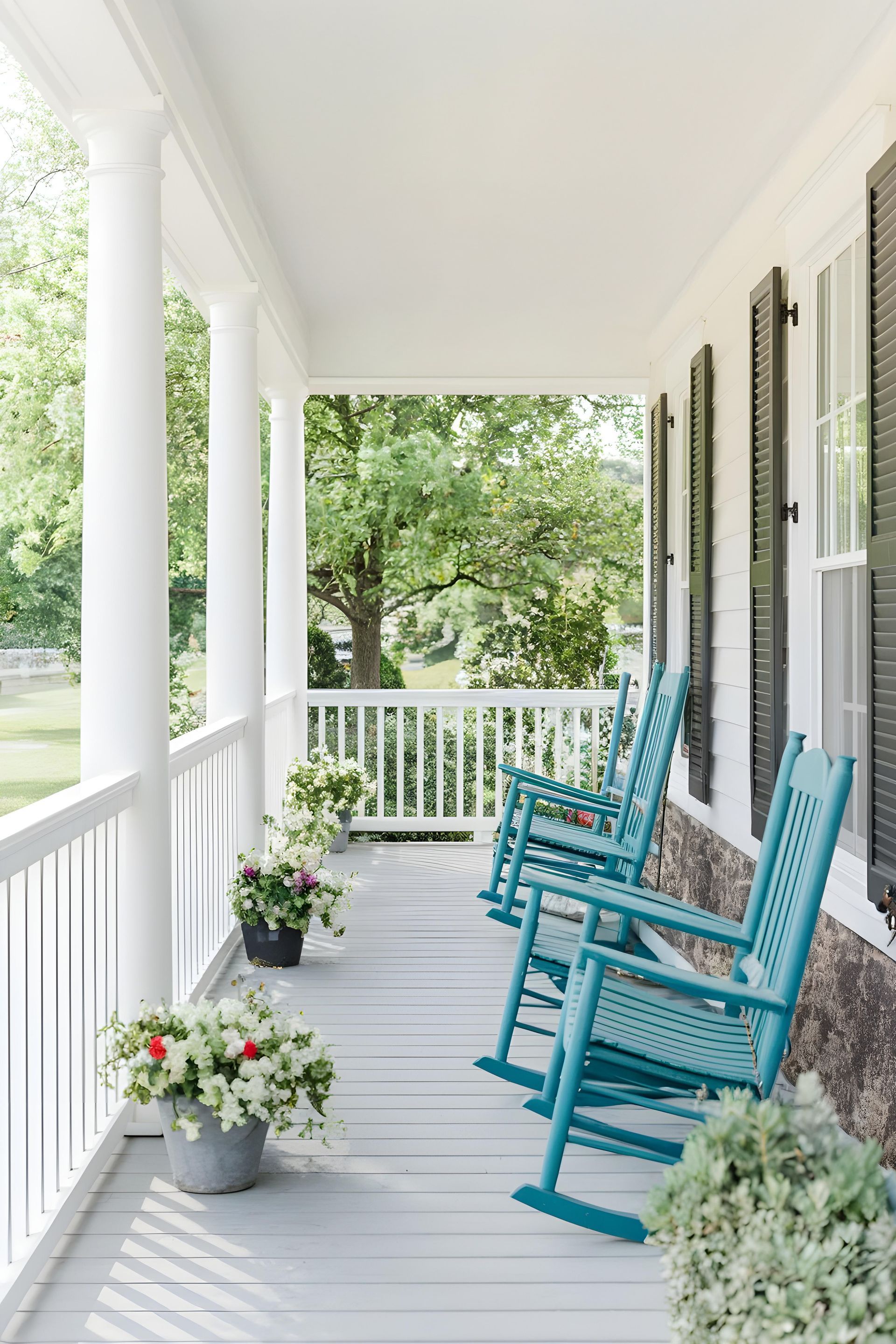 Porch with teal rocking chairs and flower pots.