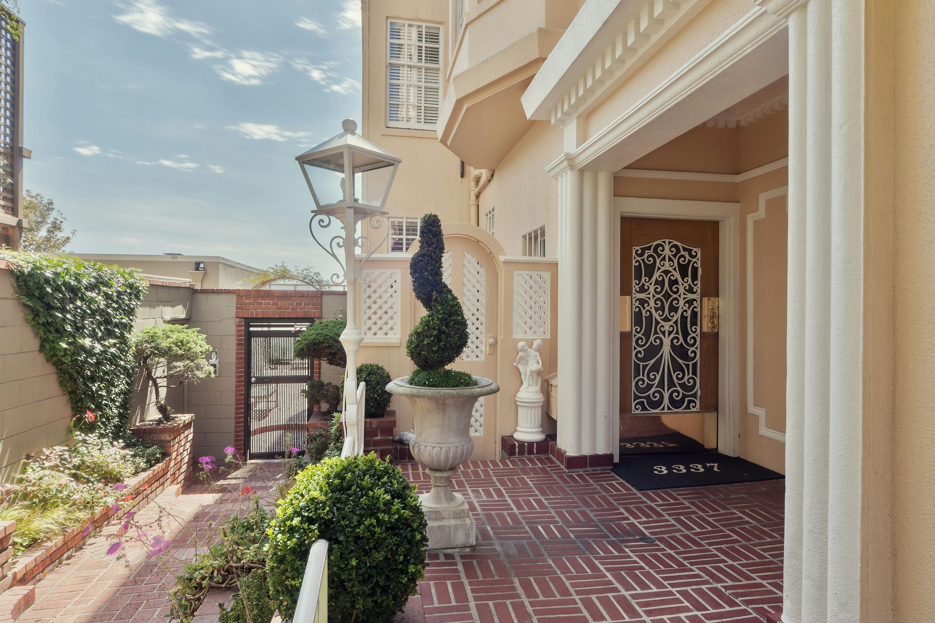 Exterior of a cream-colored building with ornate details and a decorative entryway. Brick pathway leads to the front door.