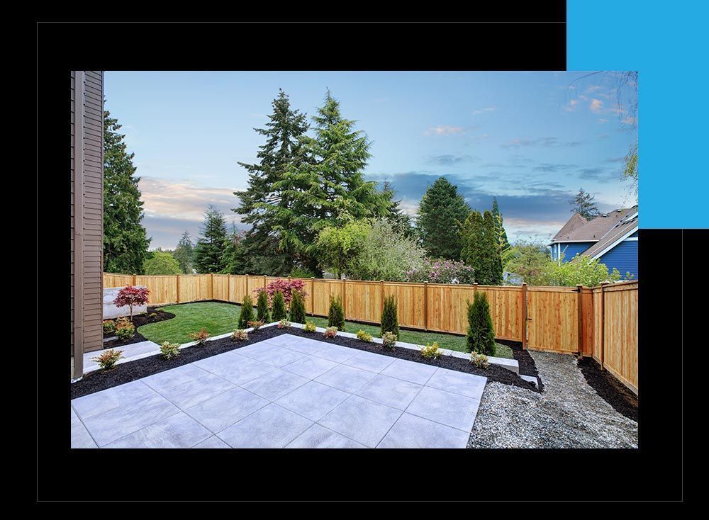 A backyard with a wooden fence and a patio.