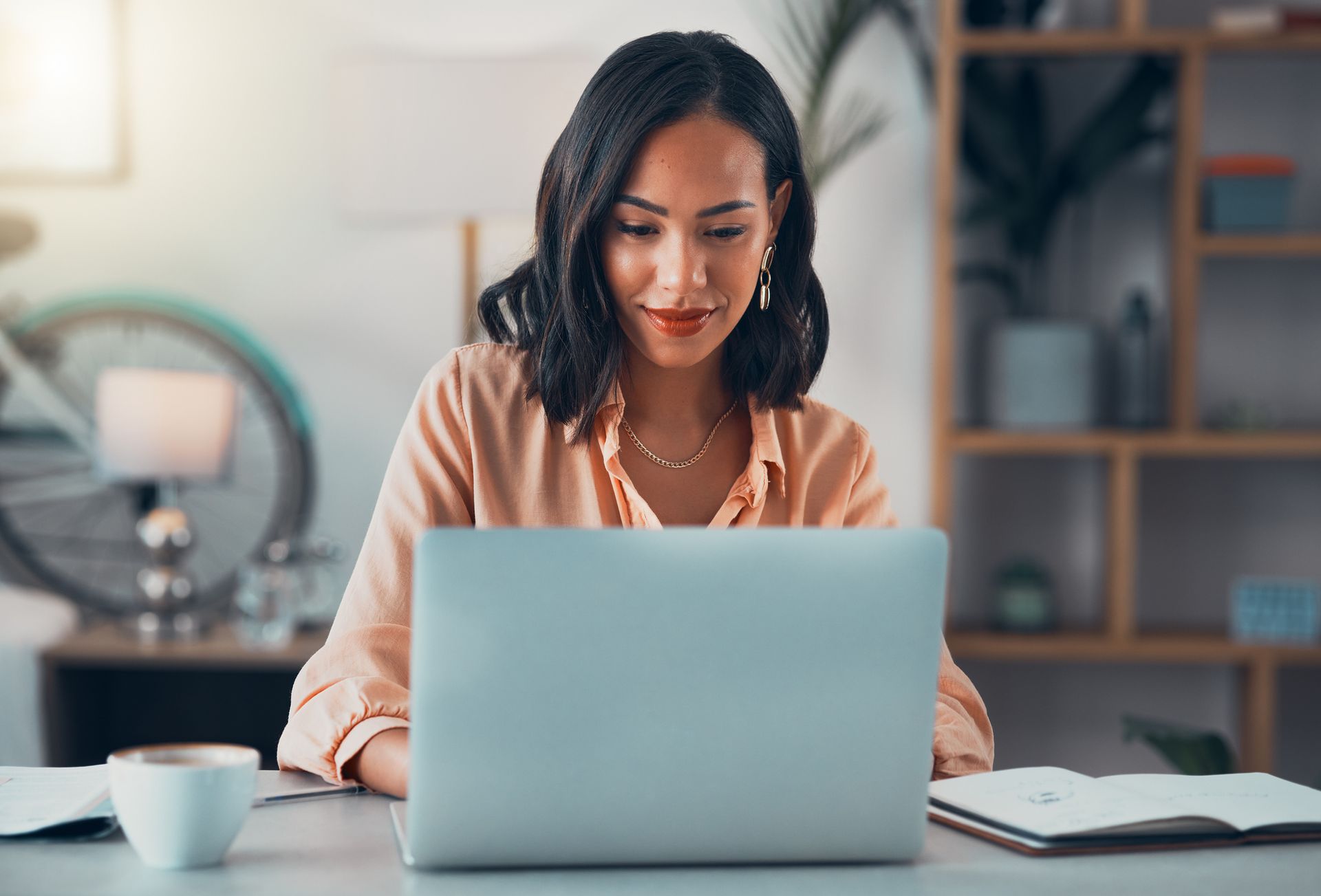 A woman is sitting at a desk using a laptop computer.