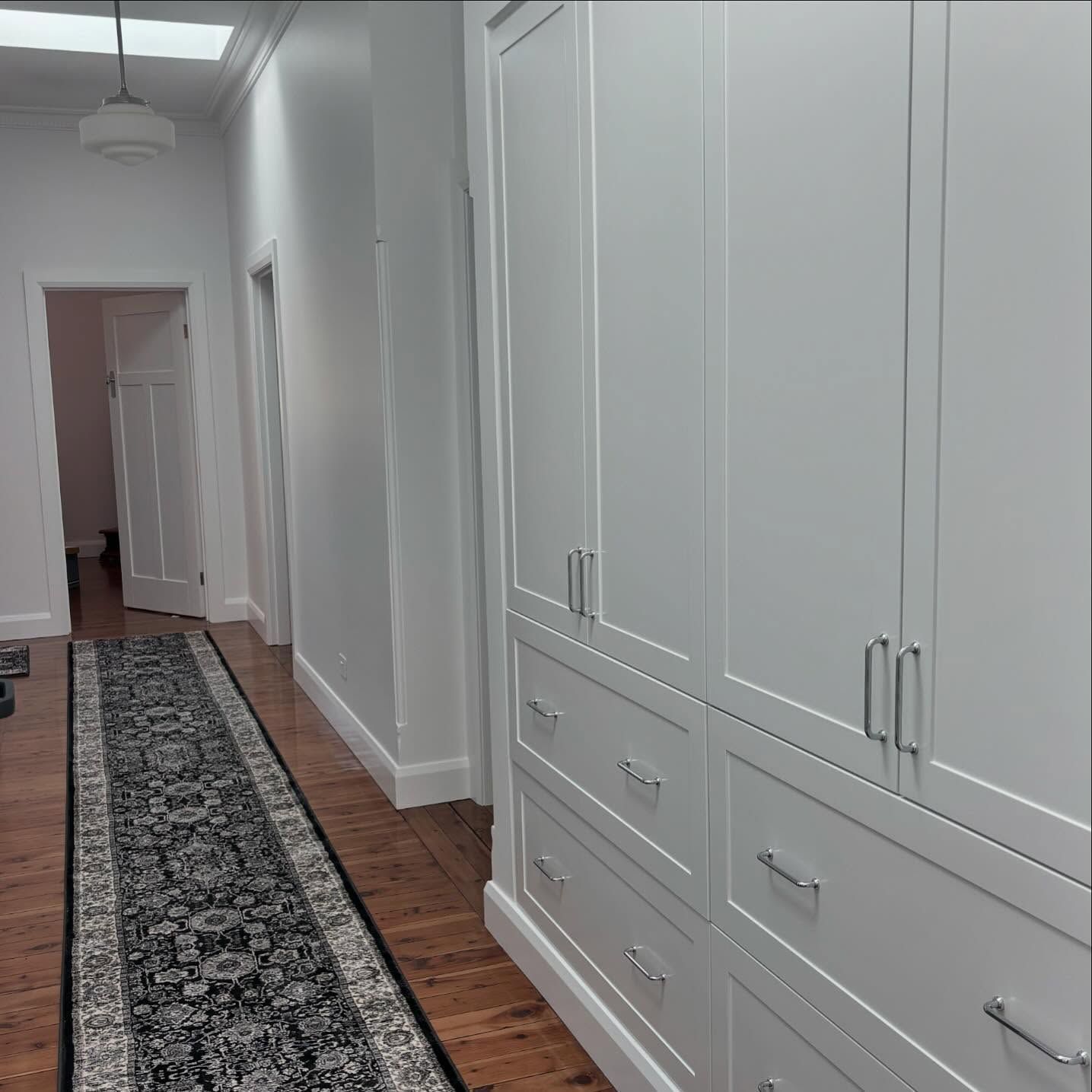 Narrow hallway with white cabinets and a patterned rug — Nielsen Construction in Wagga Wagga, NSW